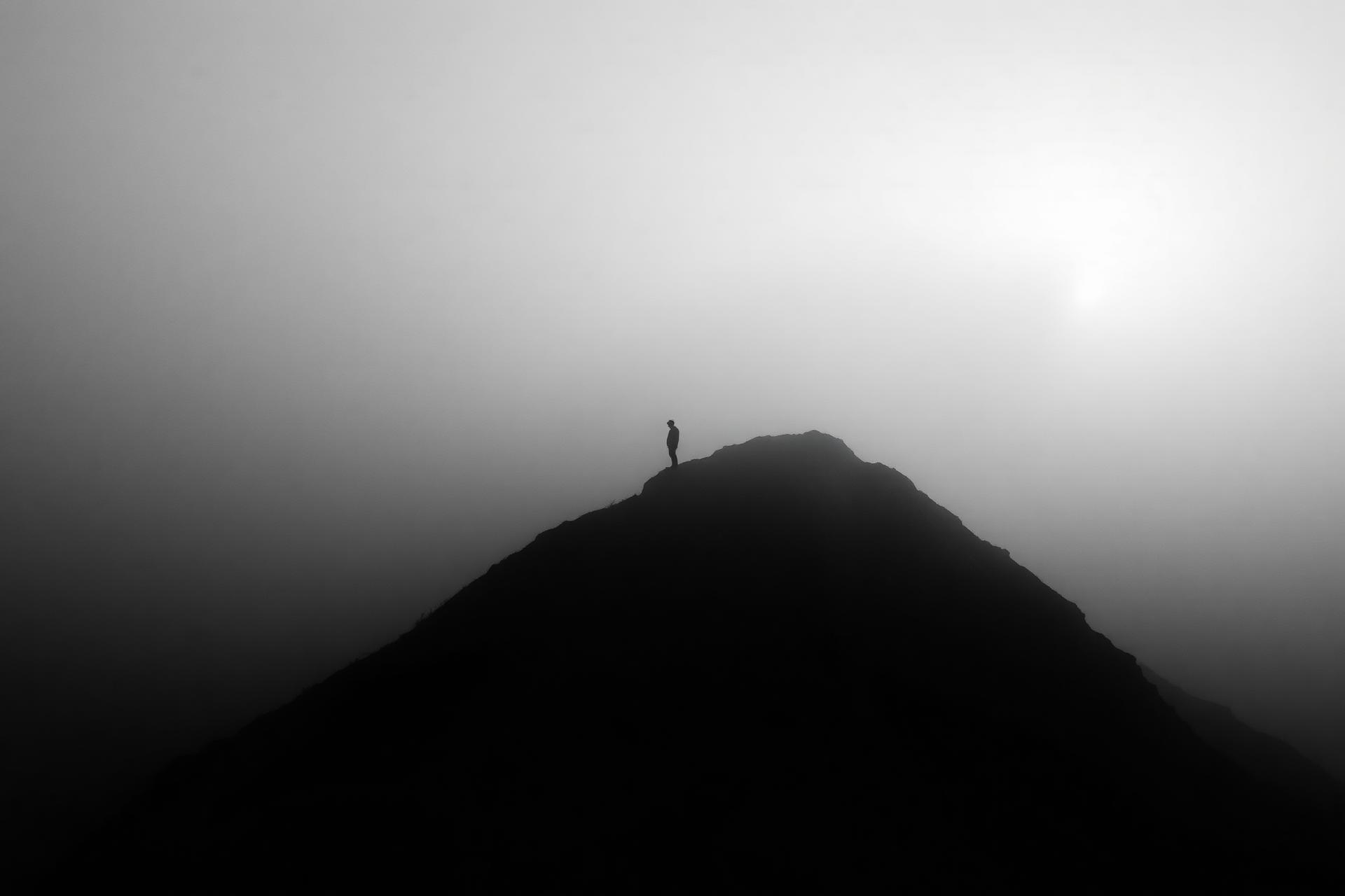 A lone figure on a misty mountain ridge at dawn